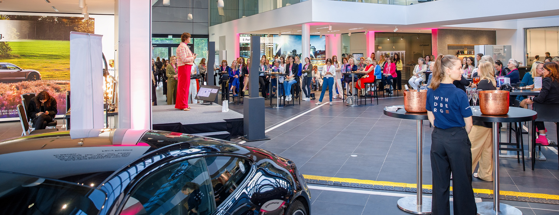 Viele Menschen stehen im Porsche Zentrum Lüneburg um eine Bühne herum.